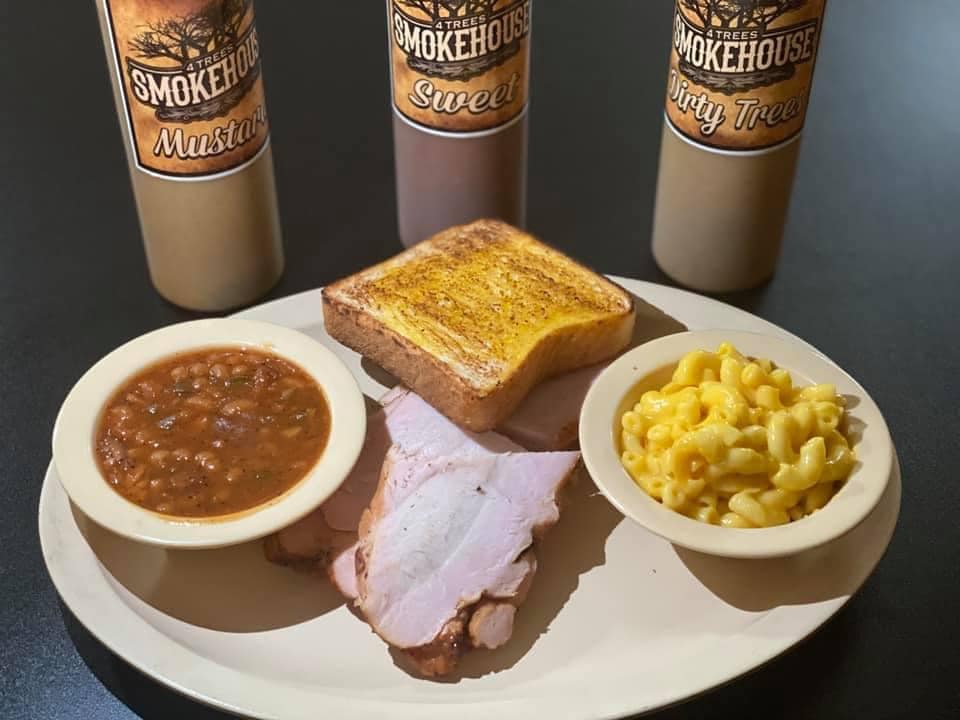 Plate of BBQ with 3 bottles of sauce.