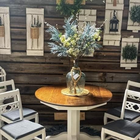 wooden table and two chairs with a vase and flowers on the center of the table