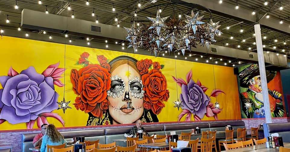 mural of mexican woman with red and purple roses and yellow background