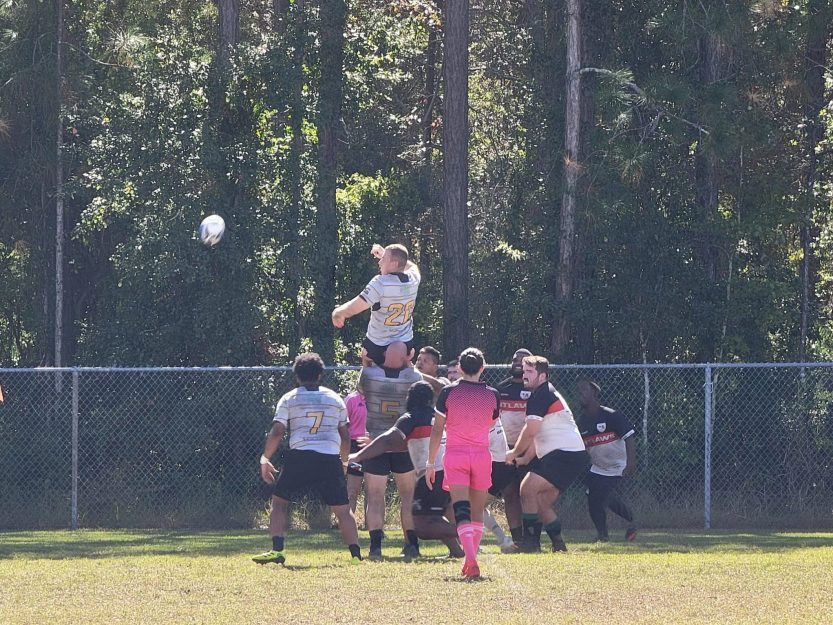 Group of athletes participating in play. One Athlete jumping for the ball.