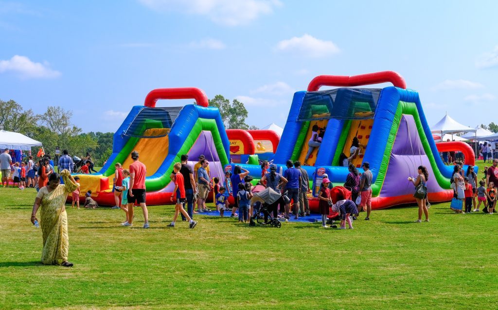 Inflatables in a large outdoor field with family and children waiting in line