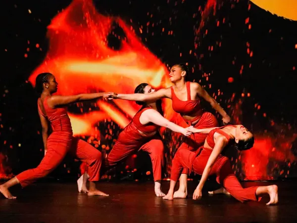 Group of dancers dressed in red, dancing on stage.