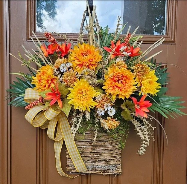flower basket with red and yellow flowers, and green leaves hanging on brown door
