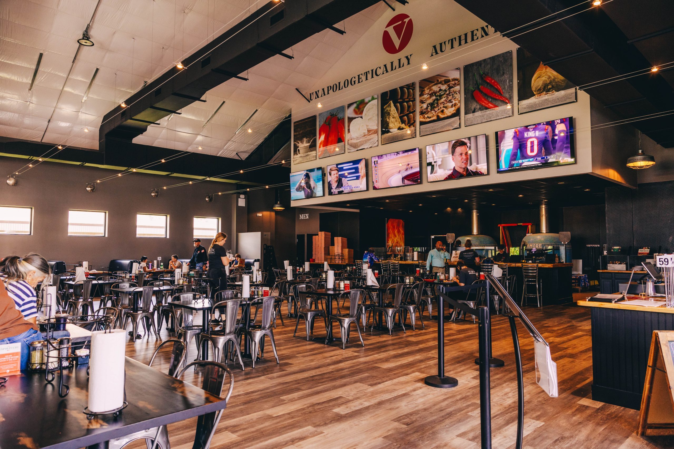 Interior of V Pizza with tables and kitchen view