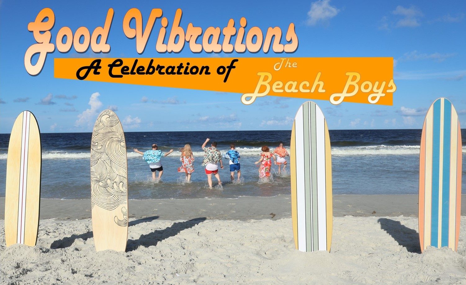 Image of beach boy actors running into the ocean with surfboards in the sand
