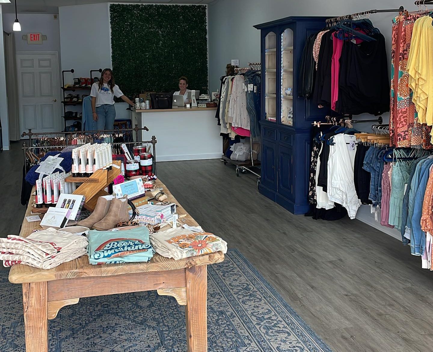 table and hanging rack display of clothing with friendly associates standing by