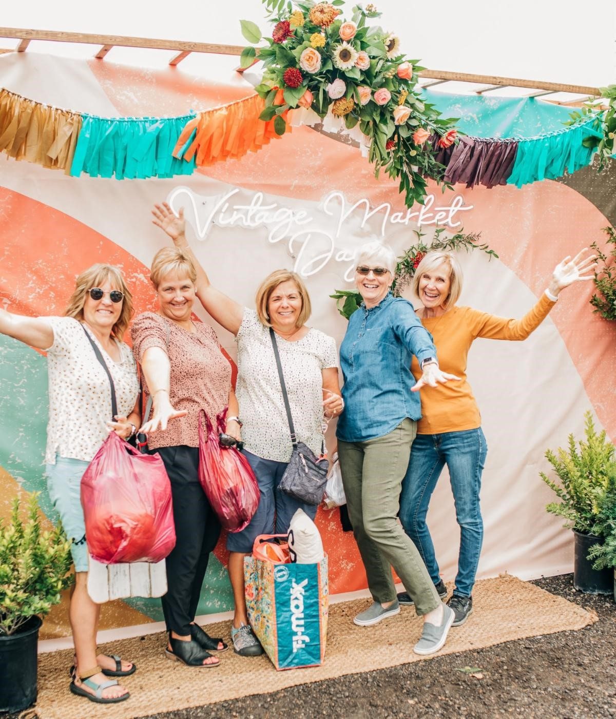 Group of women posing for picture with their shopping bags in hand.