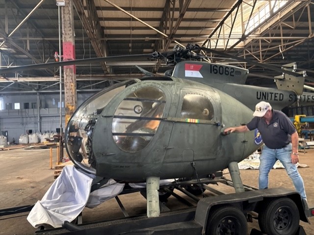 Loach Helicopter Feature Photo Photo of a man next to a retired military helicopter.