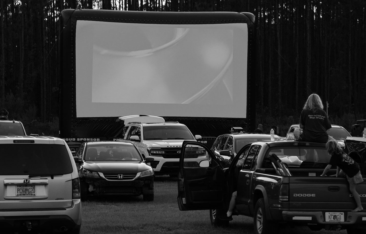 Reel Nights Feature Photo Black and white photo of cars parked in front of a movie screen.